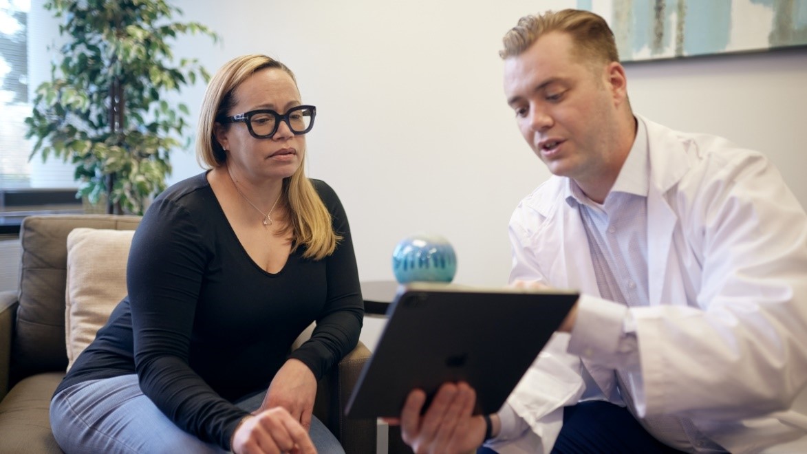 Woman and male health care provider have a conversation while provider holds and points to a tablet.