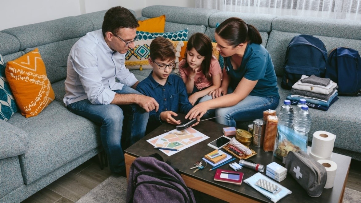 family sits together in living room and makes emergency plan
