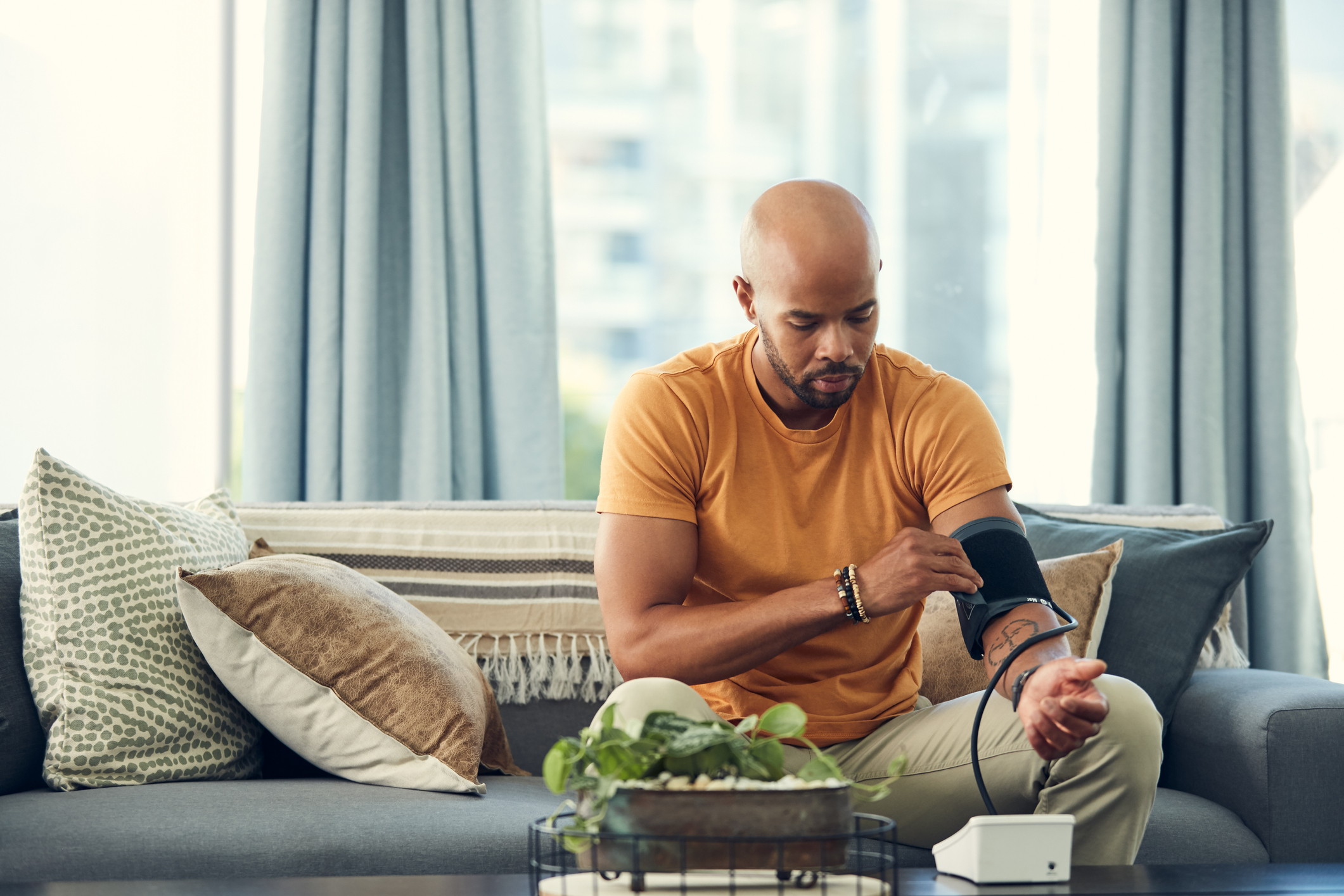 Young Black man takes his blood pressure on his couch