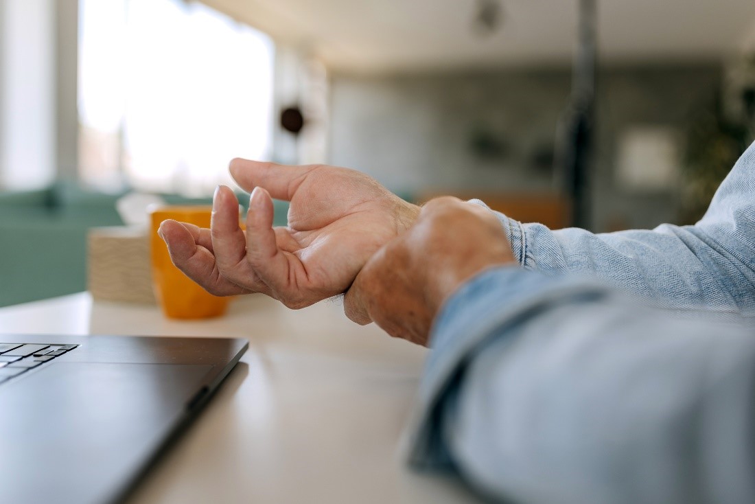 An older woman holding her wrist. 