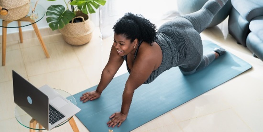 A woman stretching in front of her laptop. 