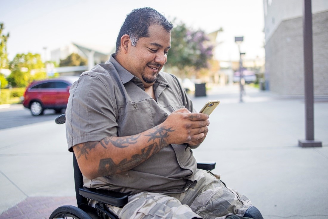 A man in a wheelchair checking his smartphone. 