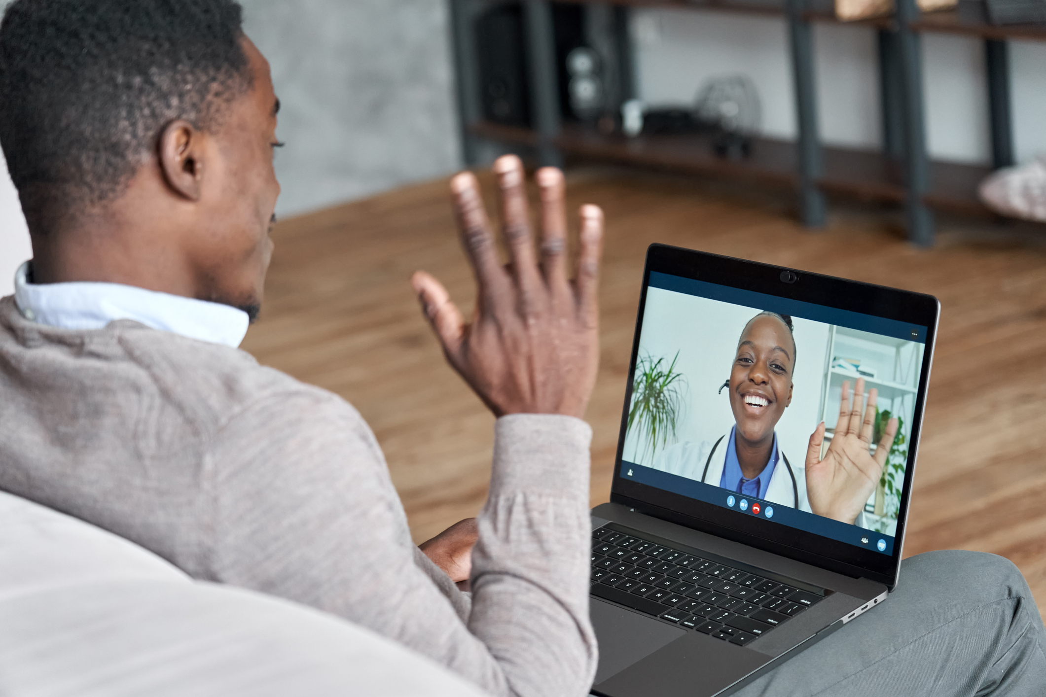 Black man waves to Black female doctor as they meet by video visit 