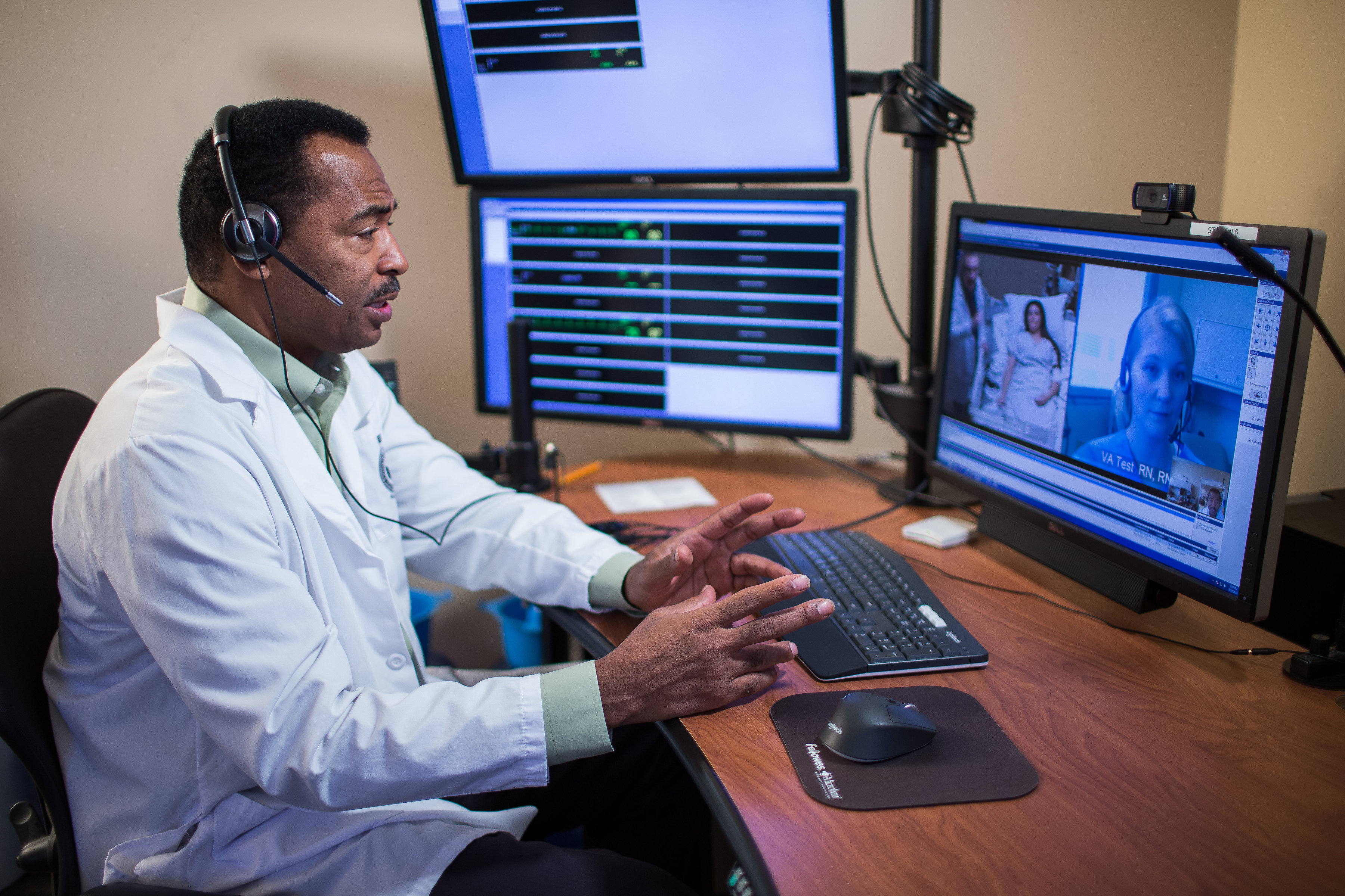 Black male provider sits in front of monitor with patient in ICU on the screen