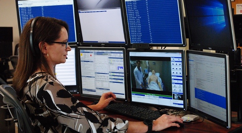 Female doctor in front of computer monitors, providing Tele-ICU care 