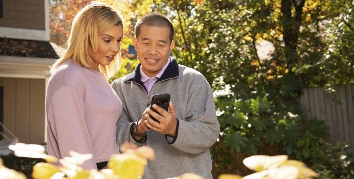 Couple holding phone and talking to doctor by video on laptop