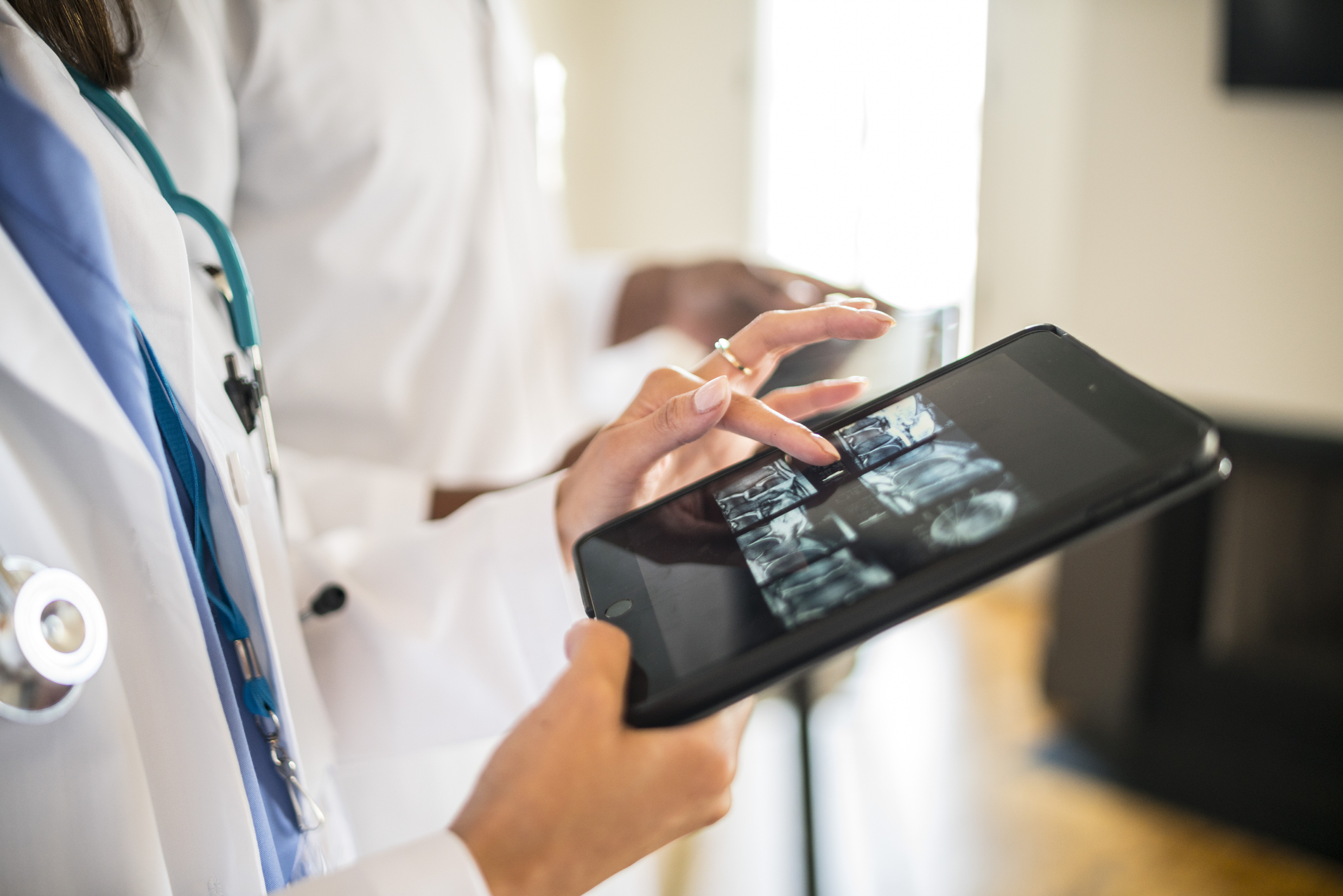 Image of doctor holding a tablet and looking at the screen.