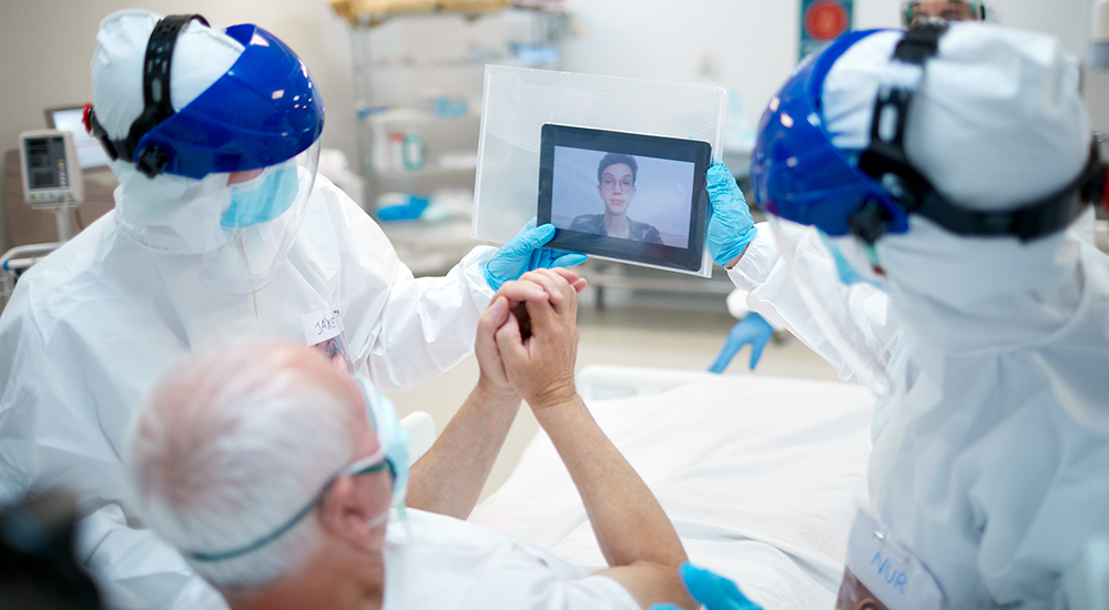 Older man in ICU speaking with loved one by video on an iPad