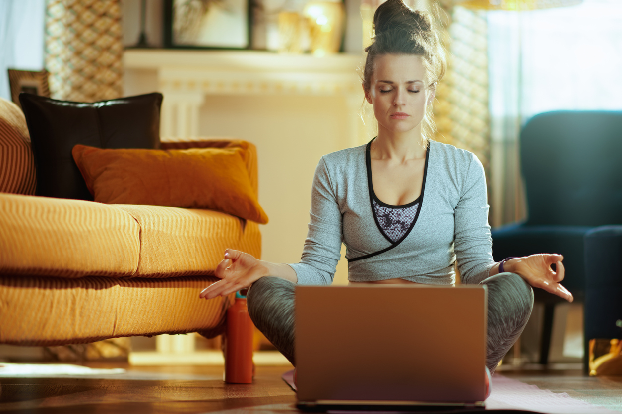 Young woman closes her eyes in meditation in front of a computer