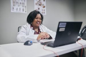Black woman provider with short hair smiles and looks at computer screen