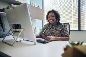 Balck female provider smiles in front of computer screen