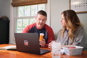 Two Veterans reviewing medications while looking at a computer.