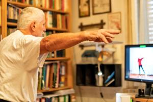 older man stretches in front of a computer monitor 