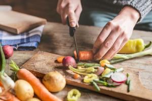 Hands cutting rainbow carrots. 