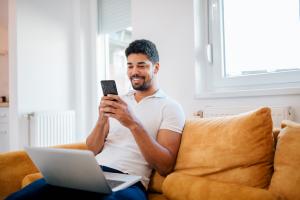 Image of man sitting on a couch using a cell phone.