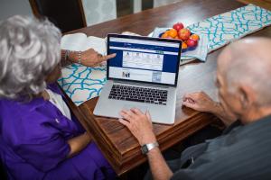 Older woman and man look at a computer with the My HealtheVet website homepage on-screen