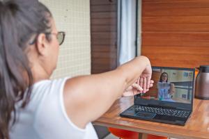 woman with brown hair stretches wrist in front of computer with provider on video