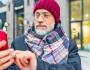 Veteran wearing a beanie and scarf checking his smartphone outside. 