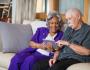 man and woman sit next to each other on couch and look at tablet