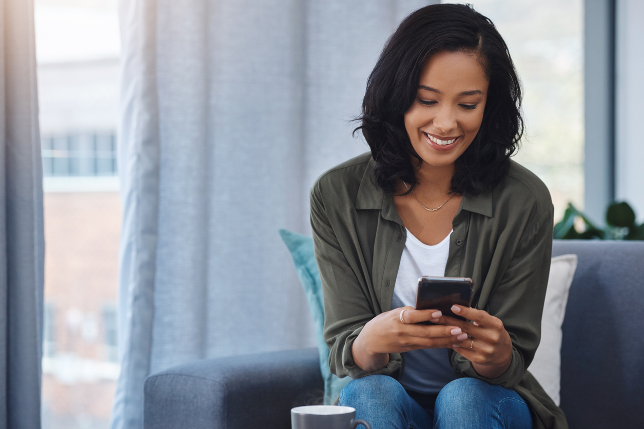 Young Black woman looks at her phone and smiles