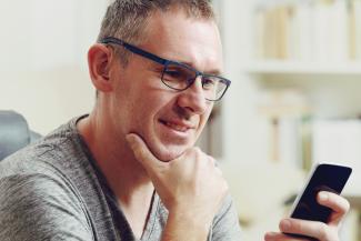 Man with grey hair holding phone and reading from it