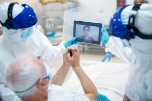 Older man in ICU speaking with loved one by video on an iPad